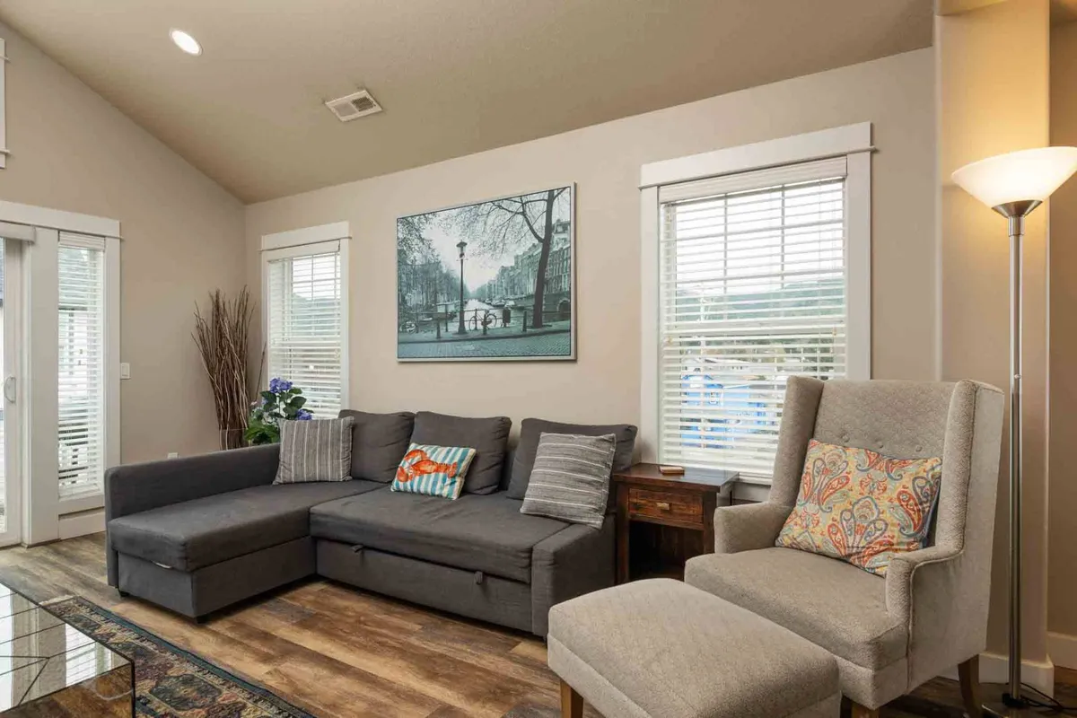 A stylish living area with a large sectional sofa, contemporary artwork, and a modern light fixture. The room exudes comfort and sociability, suggesting a welcoming space to relax, share stories, and unwind after a day out. The open layout is perfect for group gatherings and laughter.